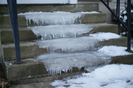 A humorous winter moment as someone slips on icy porch stairs, combining danger and laughter in a frozen outdoor scene.の素材