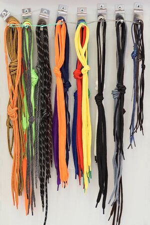 Many multi-colored shoelaces hang on a demo board for sale.                            