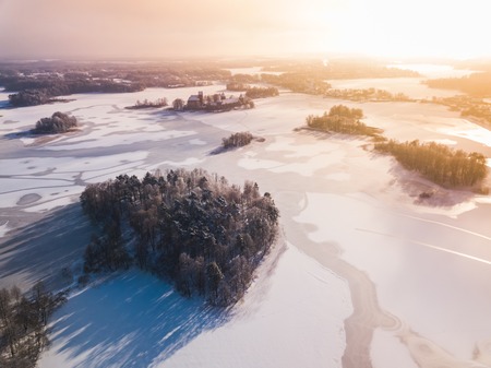Aerial view of the winter snow covered forest and frozen lake from above captured with a drone in Lithuania.の写真素材