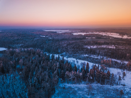 Aerial view of the winter snow covered forest and frozen lake from above captured with a drone in Lithuania.の写真素材