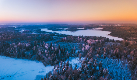 Aerial view of the winter snow covered forest and frozen lake from above captured with a drone in Lithuania.の写真素材