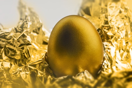 Image of shiny golden egg on golden foilの写真素材