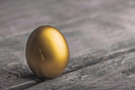 Background of Golden egg on a wooden surfaceの写真素材