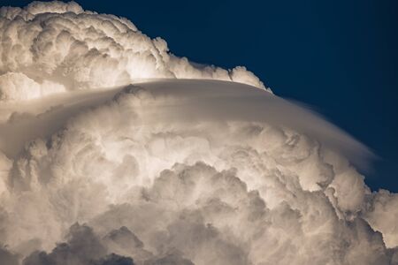 Rare Lenticular cloud Altocumulus lenticularis on top of a cumulus cloud in front of a blue skyの写真素材