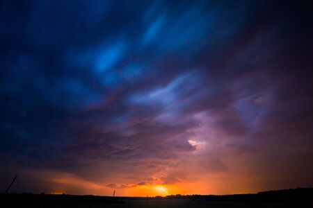 A severe thunderstorm is illuminated by a lightning bolt at night in Lithuaniaの写真素材