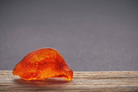 Natural amber. A piece of yellow transparent natural amber on a piece of textured woodの写真素材