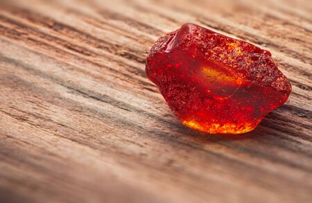 Natural amber. A piece of yellow transparent natural amber on a piece of textured woodの写真素材