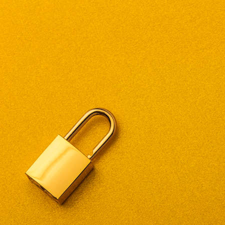 Golden lock on a golden background with empty space for textの写真素材