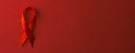 Red bow ribbon symbol HIV, AIDS cancer awareness with shadows, studio shot isolated on red...