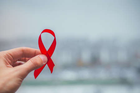 Red bow ribbon symbol HIV, AIDS cancer awareness with shadows, studio shot isolated on red...