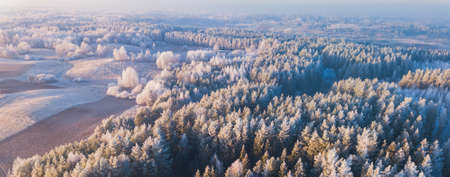 Aerial view from above of a countryside landscape with beautiful sunset light on a winter evening with forzen meadows and mist hazy horizon, bannerの写真素材