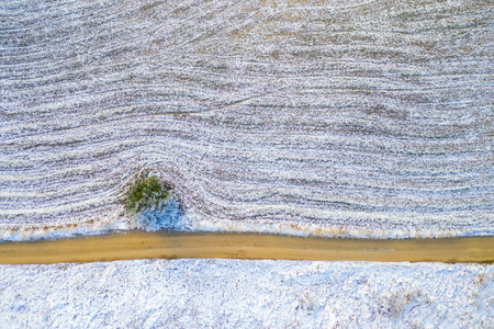 Windy winter road in snow covered forest, top down aerial view.の写真素材