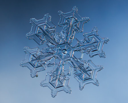 Snowflake on smooth gradient background. Macro photo of real snow crystal on glass surface. This is small snowflake with unusual pattern.の写真素材