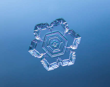Snowflake on smooth gradient background. Macro photo of real snow crystal on glass surface. This is...