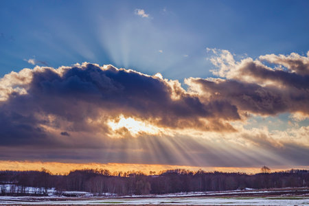 Sunset over the snowy field with sunraysの写真素材