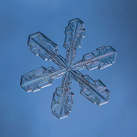 Snowflake on smooth gradient background. Macro photo of real snow crystal on glass surface. This is small snowflake with unusual pattern.の写真素材
