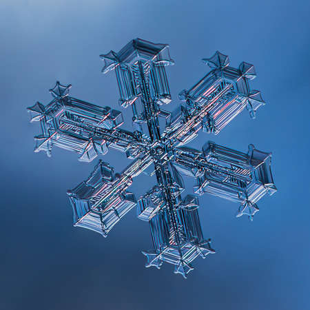 Snowflake on smooth gradient background. Macro photo of real snow crystal on glass surface. This is small snowflake with unusual pattern.の写真素材
