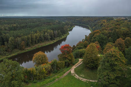 Punia mound in Lithuania with green grass and autumn trees background, road to mountainの写真素材