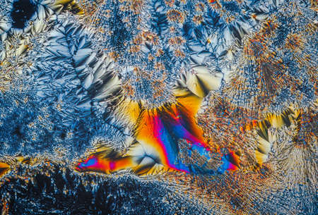 Extreme macro photograph of Vitamin C crystals forming abstract modern art patterns, when illuminated with polarized light, under a microscope objective with 10x magnificationの写真素材