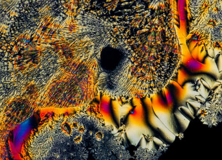 Extreme macro photograph of Vitamin C crystals forming abstract modern art patterns, when illuminated with polarized light, under a microscope objective with 10x magnificationの写真素材