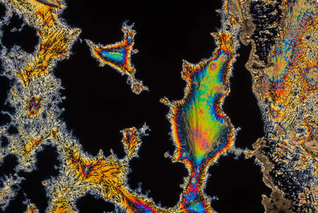 Extreme macro photograph of Vitamin C crystals forming abstract modern art patterns, when illuminated with polarized light, under a microscope objective with 10x magnificationの写真素材