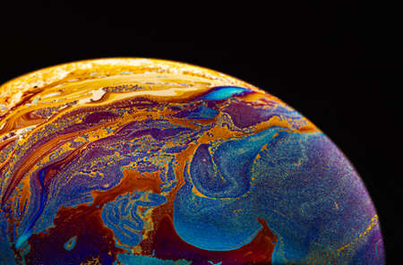 Virtual reality space with abstract multicolor psychedelic planet. Closeup Soap bubble like an alien planet on black background.の写真素材