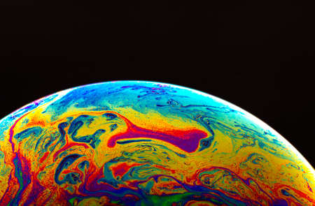 Virtual reality space with abstract multicolor psychedelic planet. Closeup Soap bubble like an alien planet on black background.の写真素材