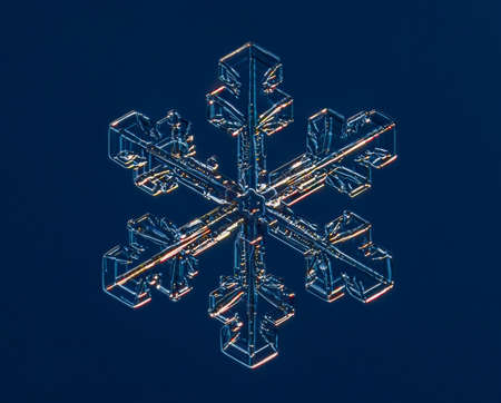 Snowflake on smooth gradient background. Macro photo of real snow crystal on glass surface. This is small snowflake with unusual pattern.の写真素材