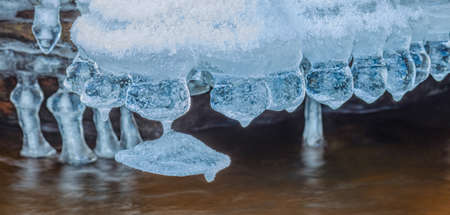 Icicles over the water in the river. Natural landscape. Winter. Background image.の写真素材