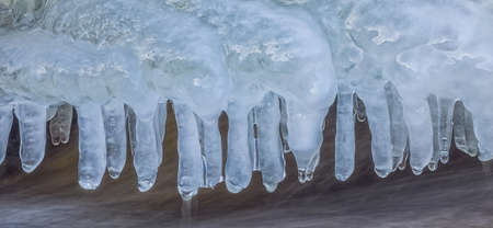 Icicles over the water in the river. Natural landscape. Winter. Background image.の写真素材