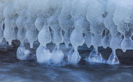 Icicles at winter, cold weather with icicles over river streamの写真素材
