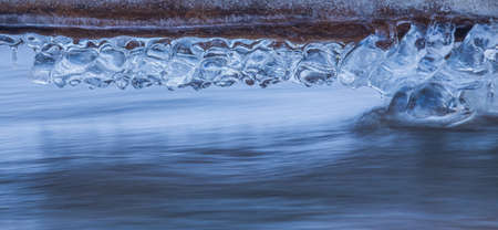 Icicles at winter, cold weather with icicles over river stream