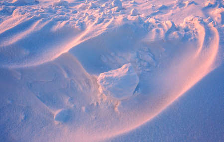 Snowdrift waves in sunset light, purple evening light at winter with a lot of snow, horizontal landscape imageの写真素材