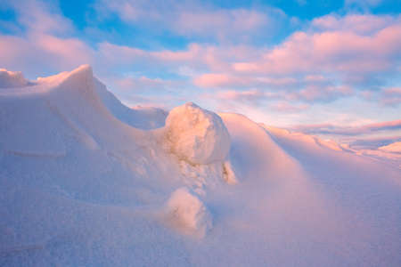 Snowdrift waves in sunset light, purple evening light at winter with a lot of snow, horizontal landscape imageの写真素材