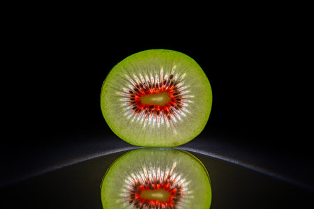 Slice of akiwi isolated in dark black background with reflectionの写真素材