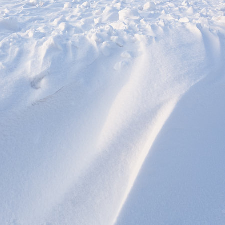 Snowdrift waves in sunset light, winter background of snow wavesの写真素材