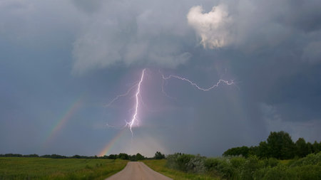 Lightning strike over the rainbow. Stormy landscape.の写真素材