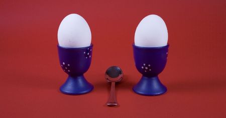 two eggs in blue glass on red background