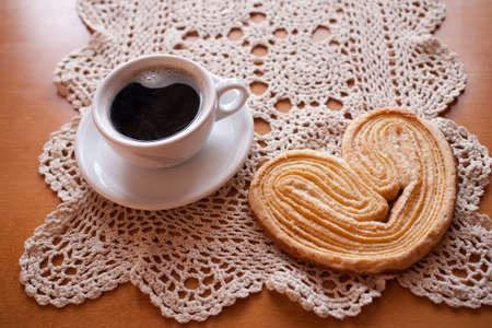 a small white cup of black coffee and a sweet buttery cookie on the tableの写真素材