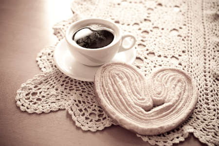a small white cup of black coffee and a sweet buttery cookie on the tableの写真素材