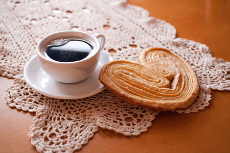 a small white cup of black coffee and a sweet buttery cookie on the tableの写真素材