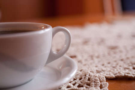 a small white cup with black coffee on a hand-made tableclothの写真素材