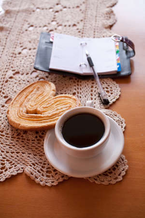 a small white cup of black coffee and a sweet buttery cookie on the tableの写真素材