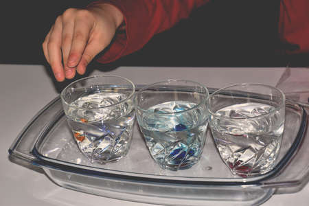 little boy's hand doing an experiment with water and colors
