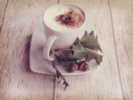 warm, hot autumn coffee with foam and chestnuts on a wooden backgroundの写真素材