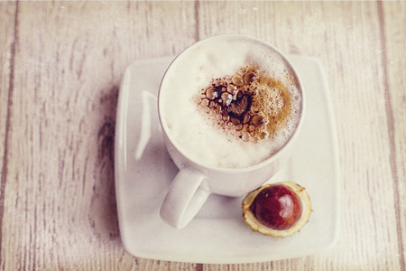 warm, hot autumn coffee with foam and chestnuts on a wooden backgroundの写真素材