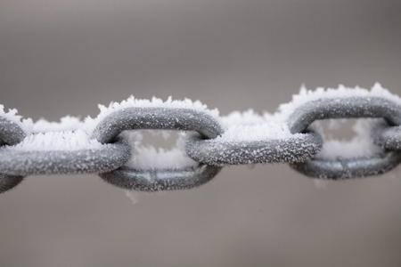 a metal chain covered with white frost on a pastel background