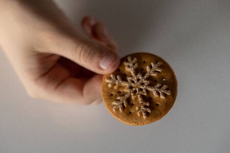 beautiful tasty gingerbread with white snowflake decoration for Christmas kept in the hand of a chilの写真素材