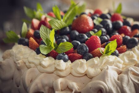 meringue cake with colorful fresh fruit and mint in close-up