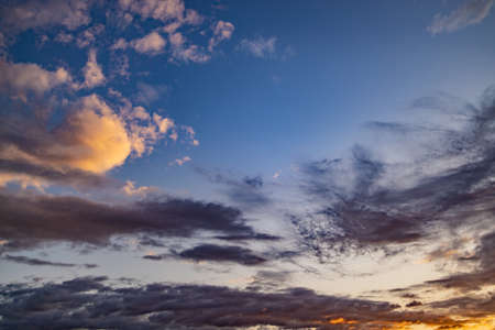 beautiful evening blue sky with dark clouds lit by the orange sun